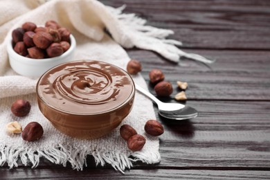 Bowl with delicious chocolate paste and nuts on wooden table. Space for text