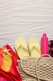 Flat lay composition with wicker bag and other beach accessories on sand. Space for text