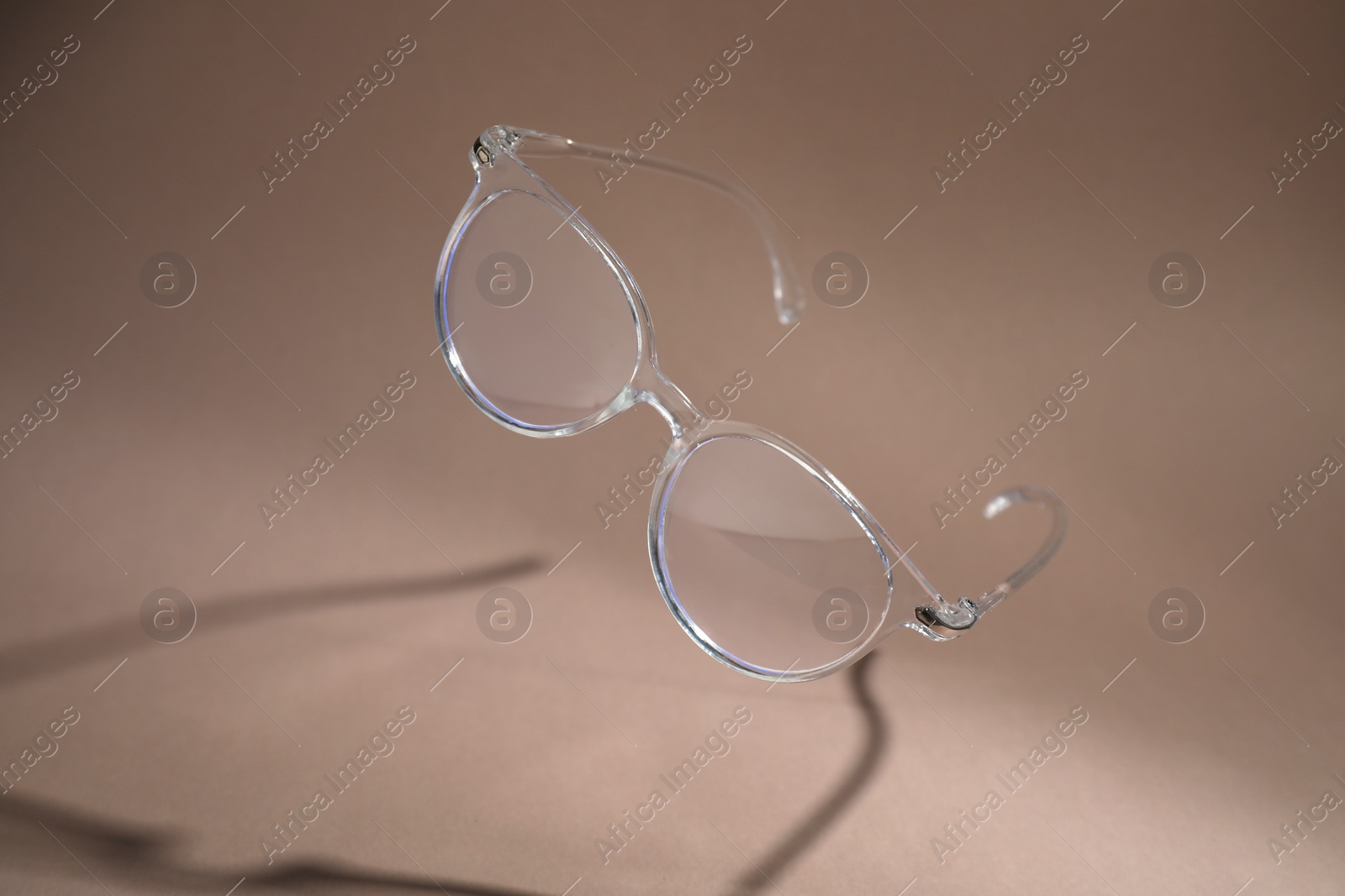 Photo of Stylish pair of glasses on pale brown background