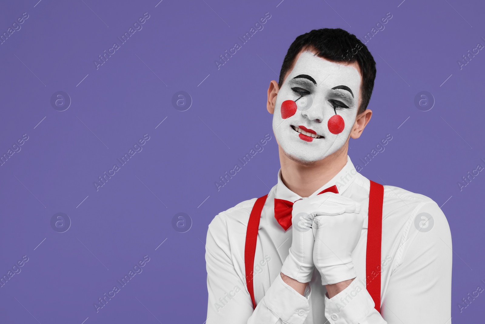 Photo of Funny mime artist posing on purple background. Space for text