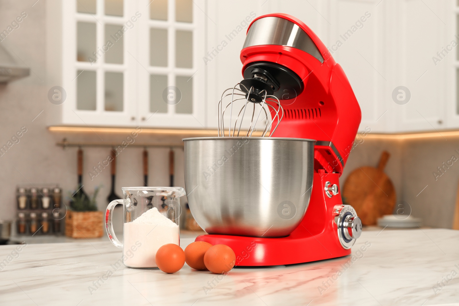 Photo of Modern red stand mixer, eggs and container with flour on white marble table in kitchen