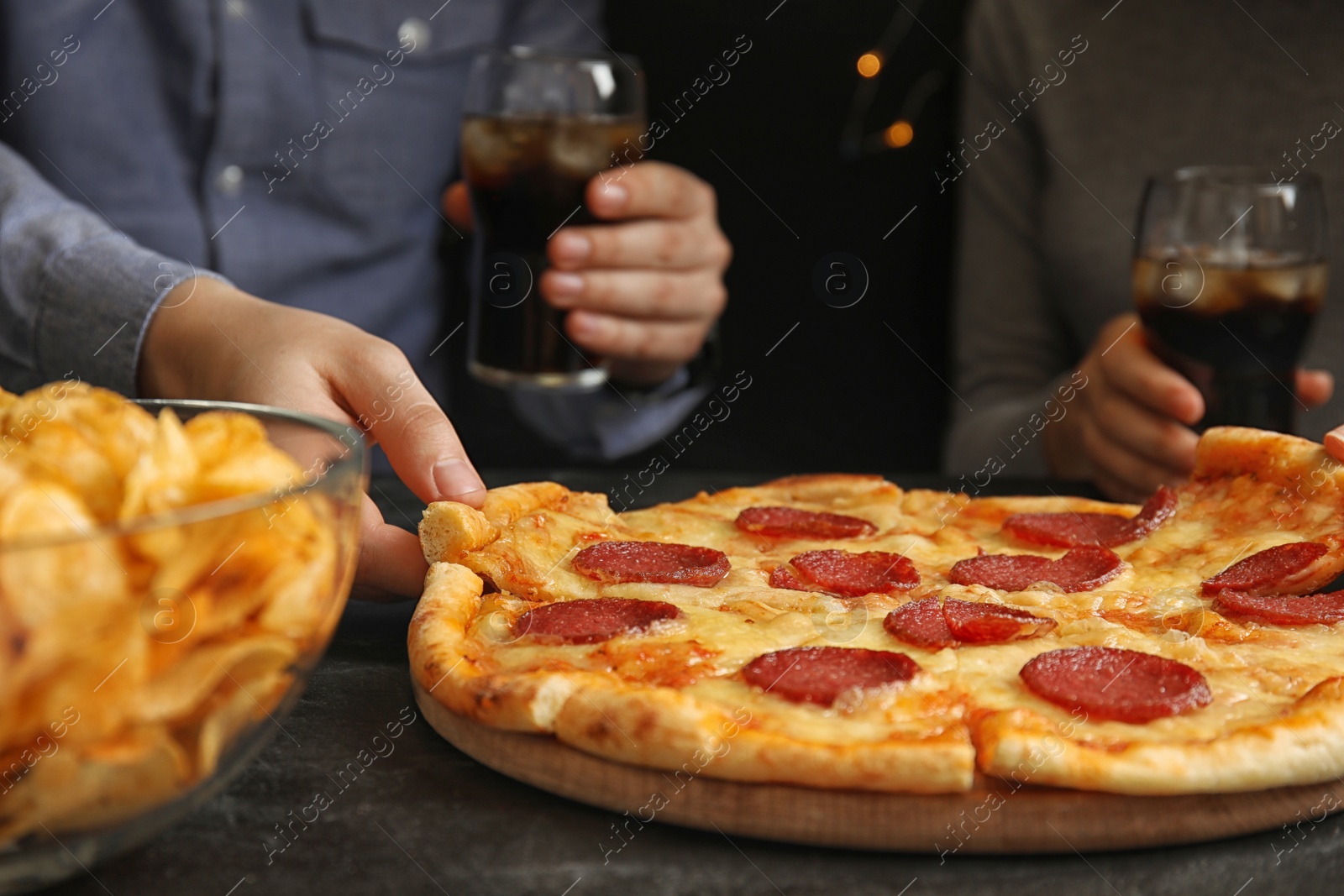 Photo of Friends taking tasty pepperoni pizza at table, closeup