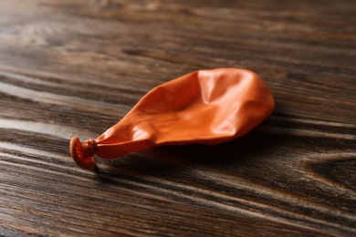 Photo of Orange deflated latex balloon on wooden background