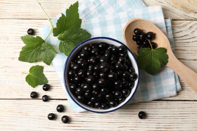 Photo of Ripe blackcurrants and leaves on light wooden table, flat lay