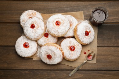 Many delicious donuts with jelly and powdered sugar on wooden table, flat lay