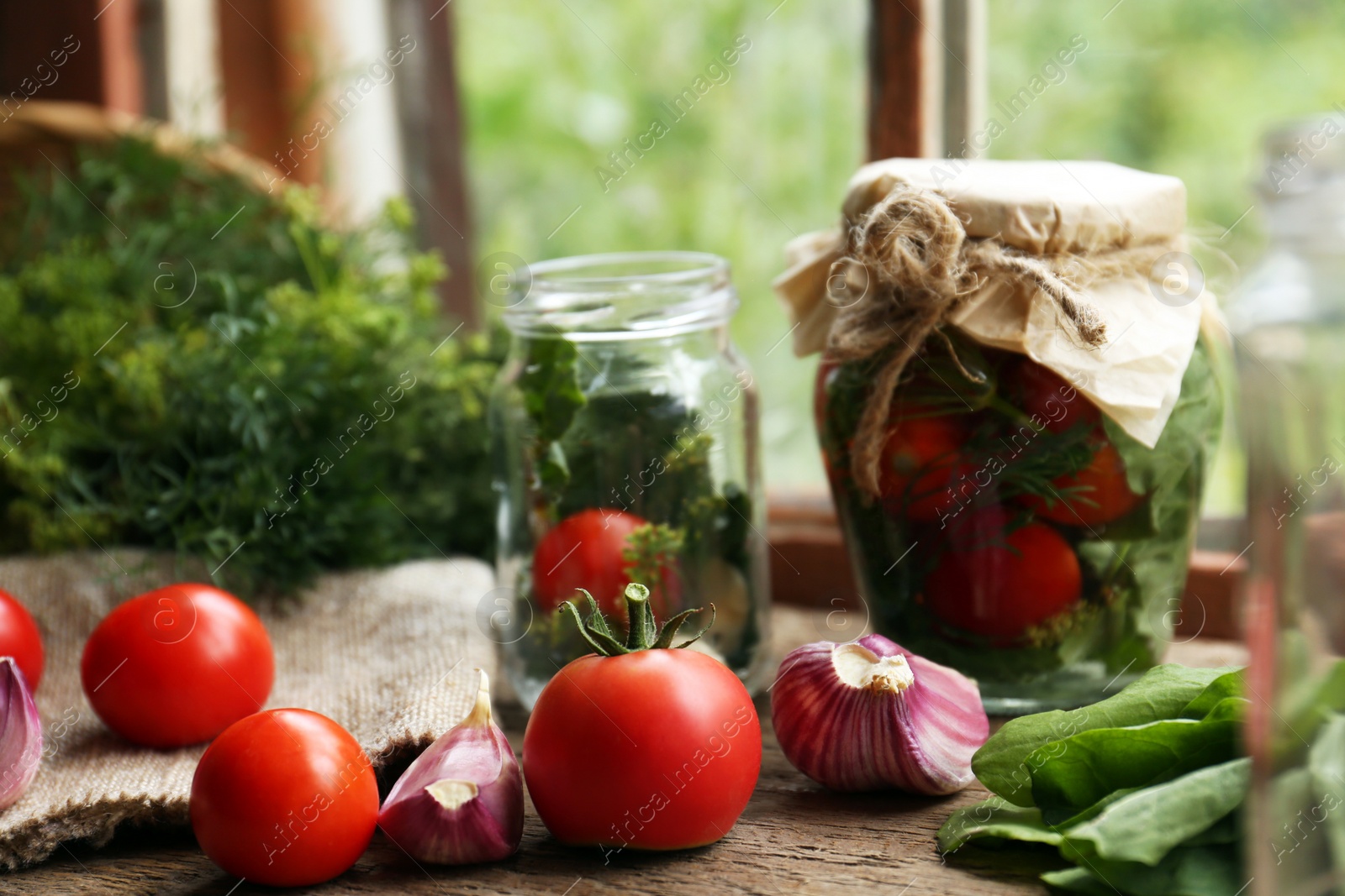 Photo of Glass jars, fresh vegetables and herbs on wooden table indoors. Pickling recipe