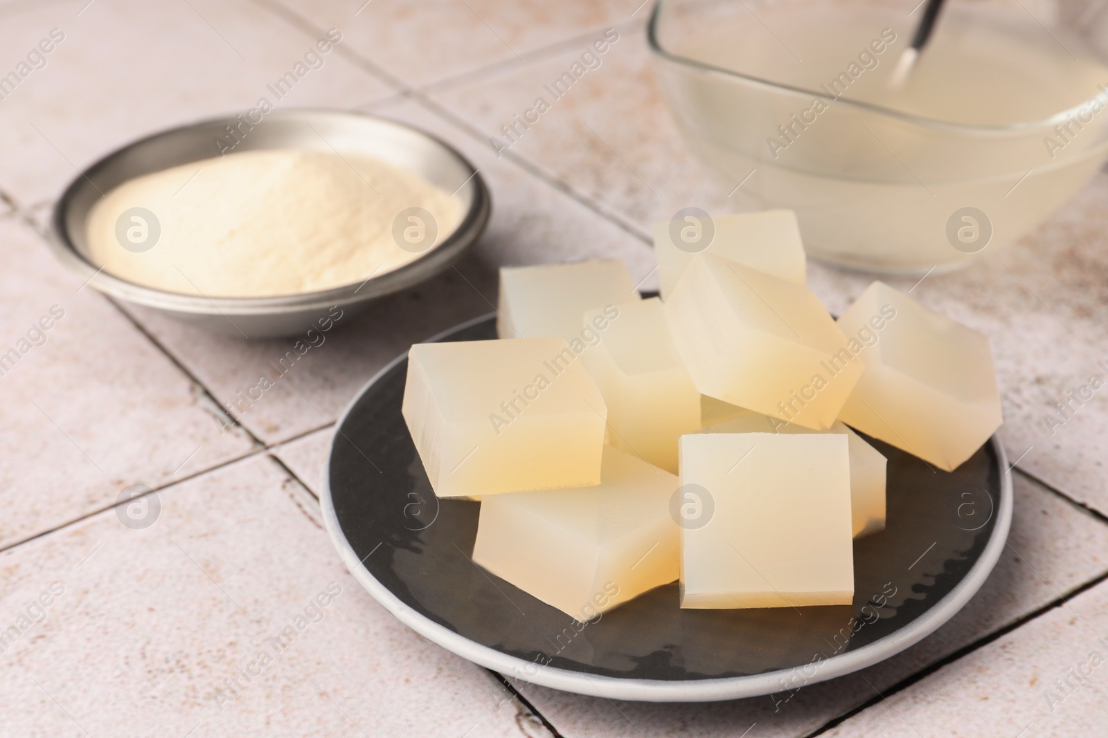 Photo of Agar-agar jelly cubes and powder on tiled surface, closeup