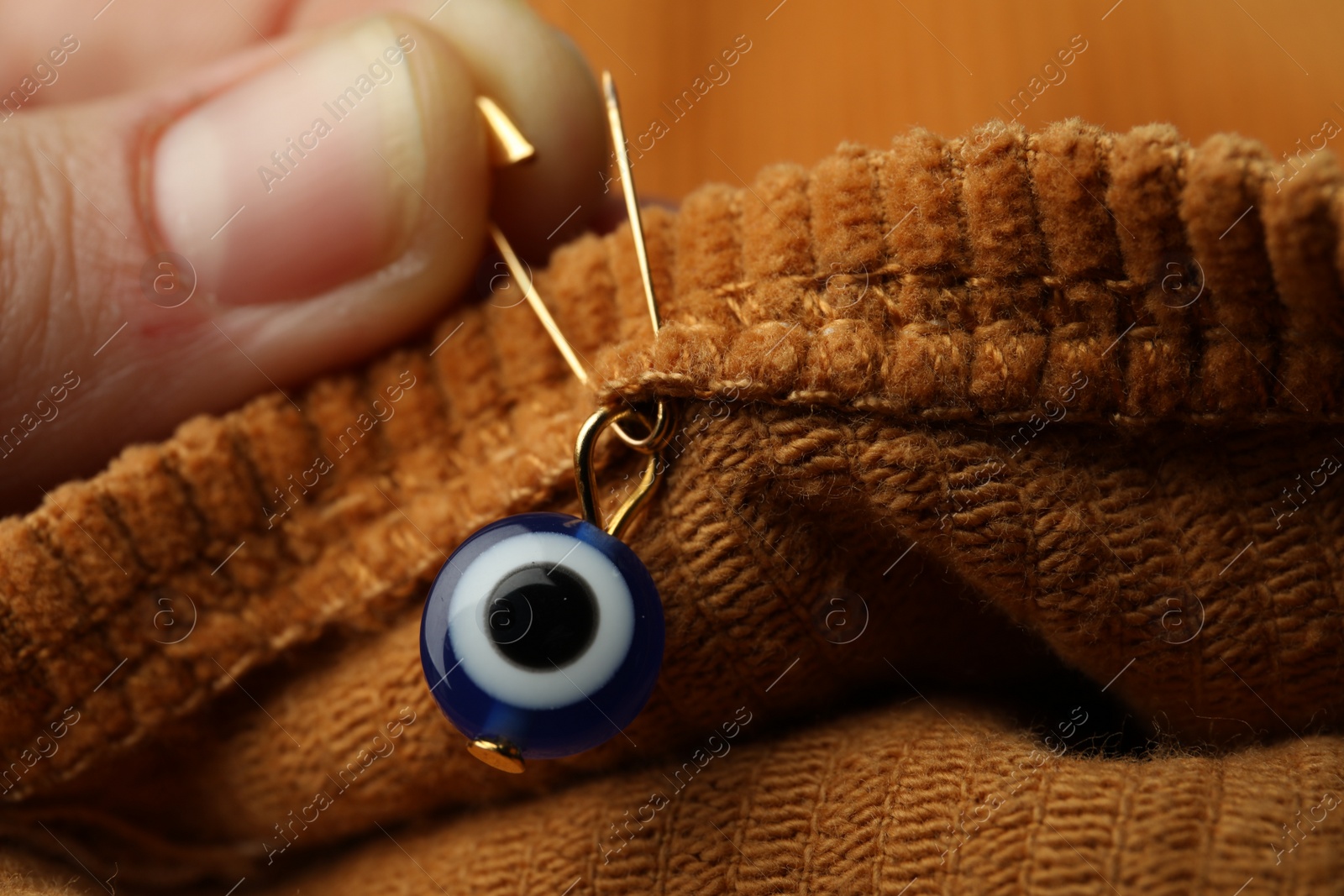 Photo of Woman pinning evil eye amulet on clothing, closeup