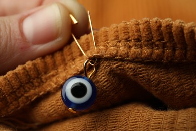 Photo of Woman pinning evil eye amulet on clothing, closeup