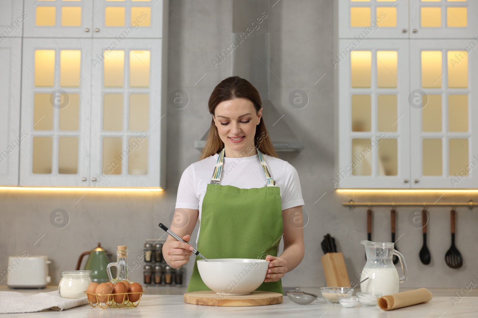 Photo of Making bread. Woman preparing dough in bowl at white table in kitchen