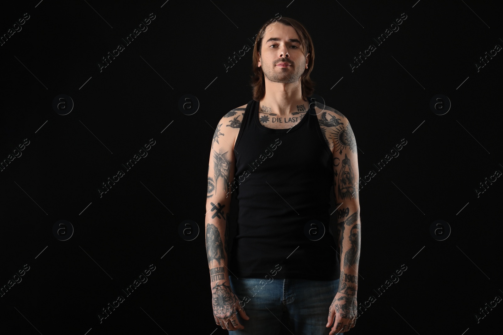 Photo of Young man with tattoos on body against black background