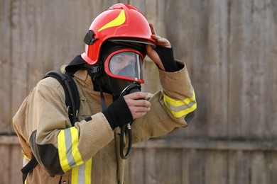 Photo of Firefighter in uniform wearing helmet and mask outdoors