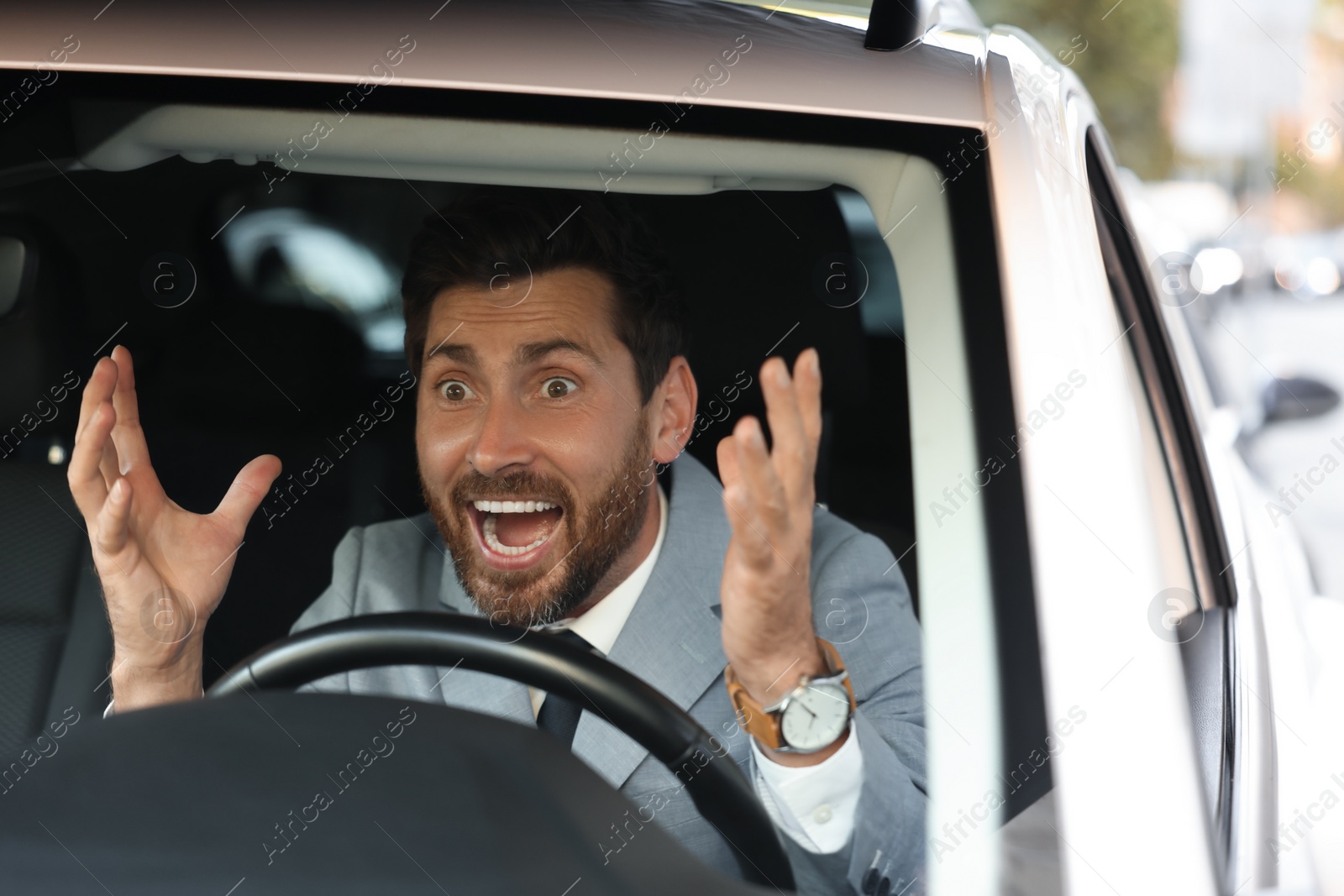 Photo of Angry driver screaming in his car, view through windshield. Stuck in traffic jam