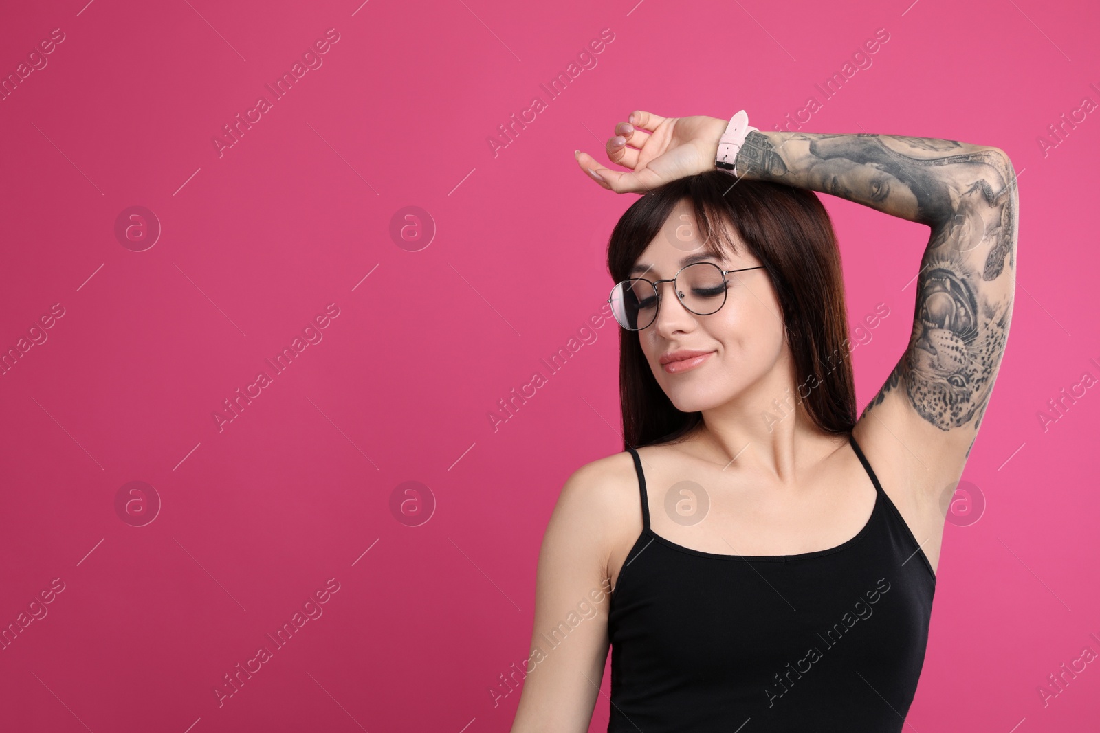 Photo of Woman with tattoos on arm against pink background. Space for text