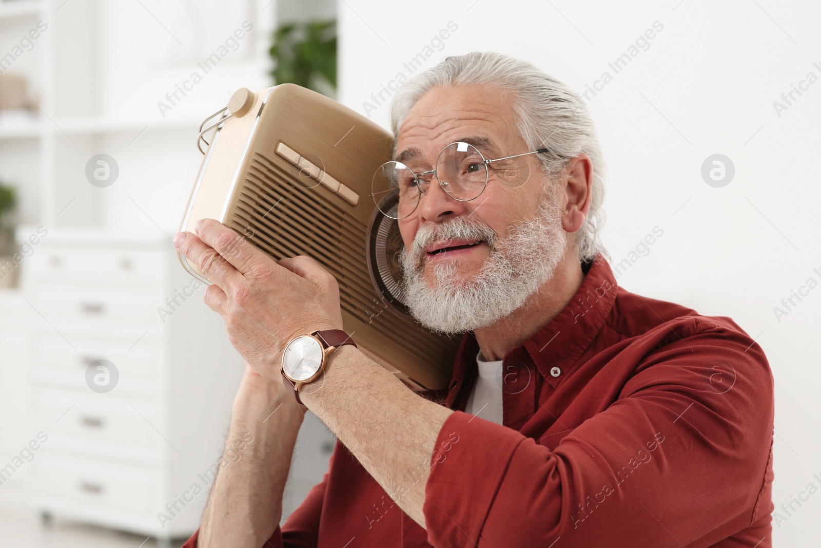 Photo of Senior man with retro radio receiver at home