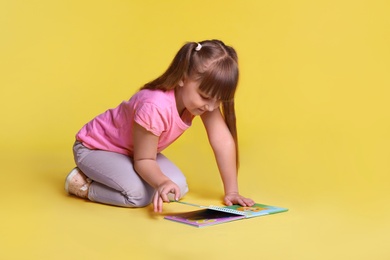 Photo of Portrait of cute little girl reading book on light green background