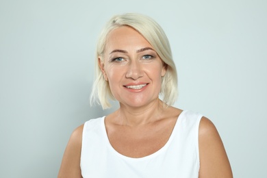 Portrait of mature woman with beautiful face on grey background