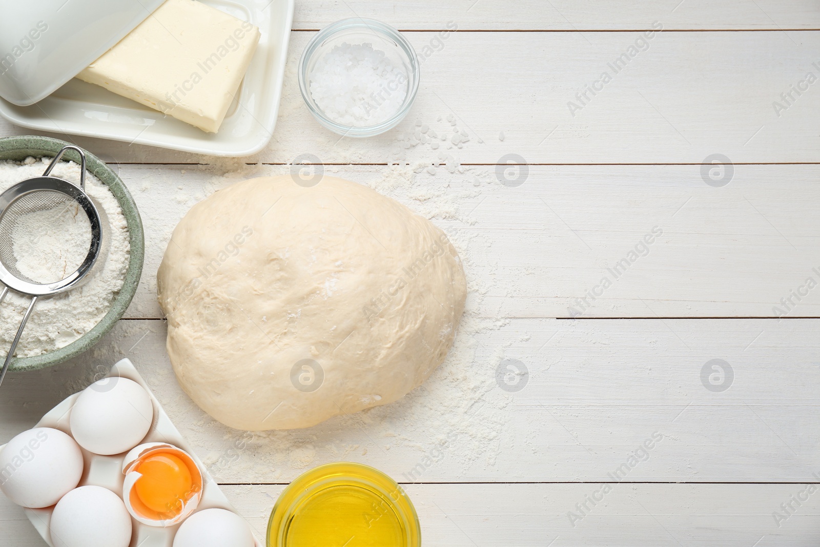 Photo of Fresh yeast dough and ingredients on white wooden table, flat lay. Space for text