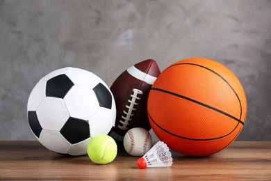 Set of different sport balls and shuttlecock on wooden table