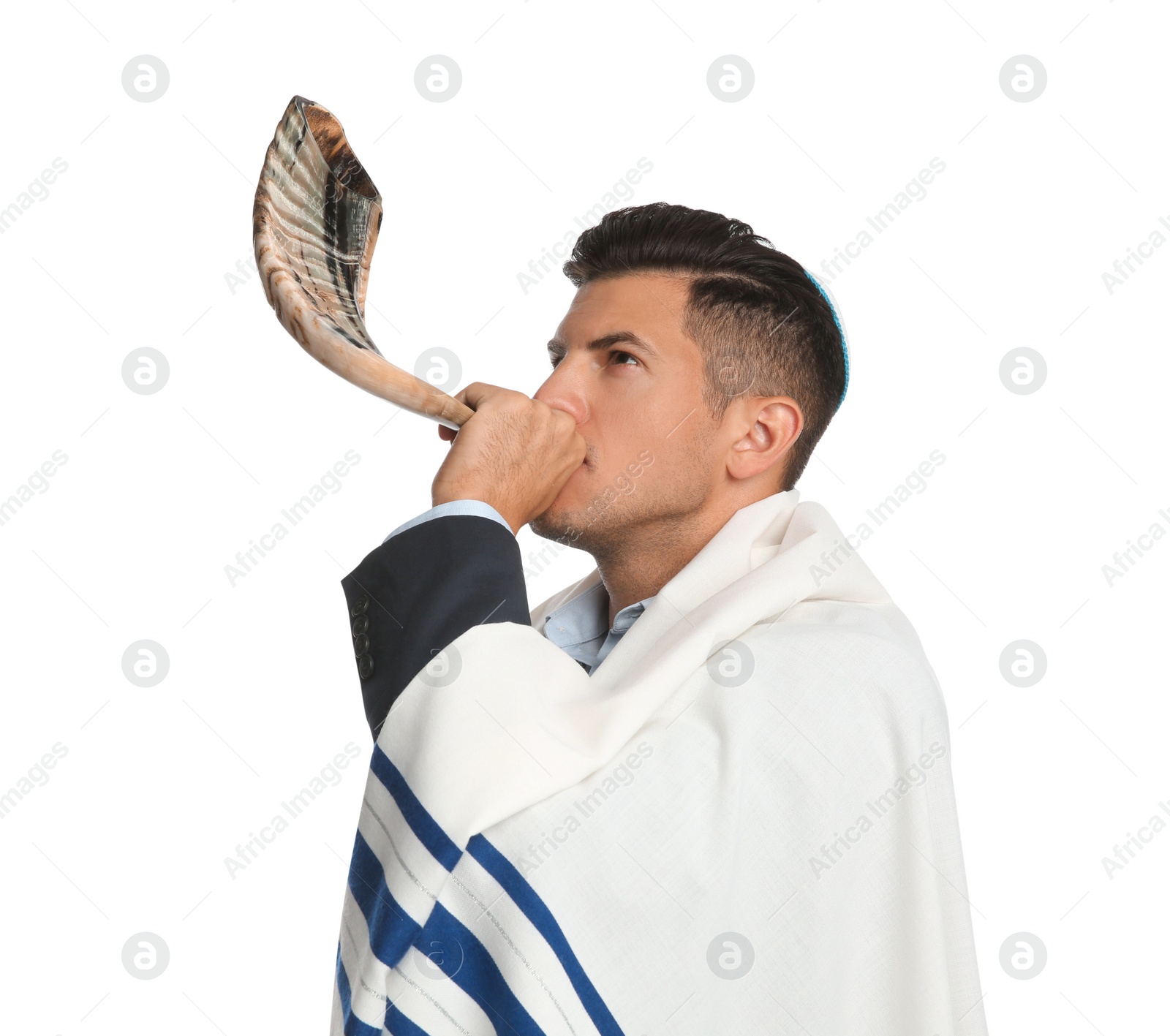 Photo of Jewish man with kippah and tallit blowing shofar on white background. Rosh Hashanah celebration