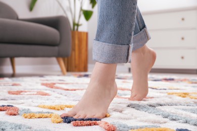 Photo of Woman standing on soft carpet at home, closeup