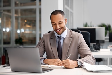 Photo of Happy man working at table in office. Lawyer, businessman, accountant or manager