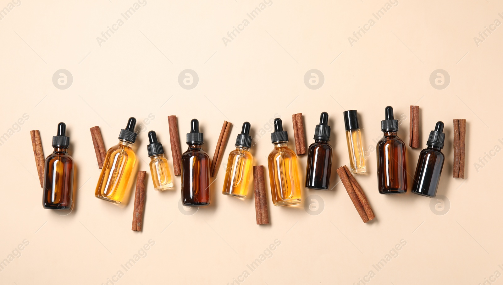 Photo of Flat lay composition with cinnamon essential oil on beige background