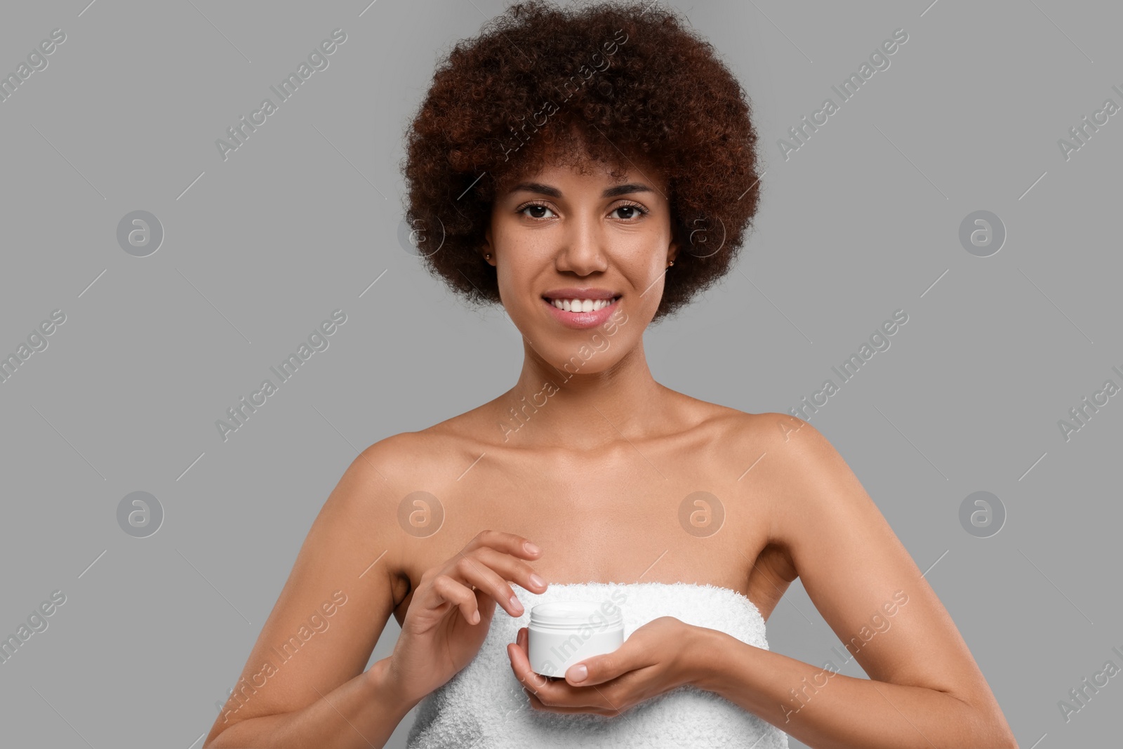 Photo of Beautiful young woman holding body cream on grey background