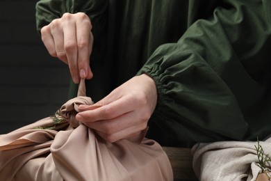 Photo of Furoshiki technique. Woman wrapping gift in fabric, closeup