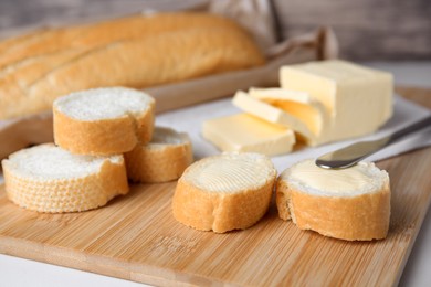 Photo of Tasty cut baguette with fresh butter on white table, closeup