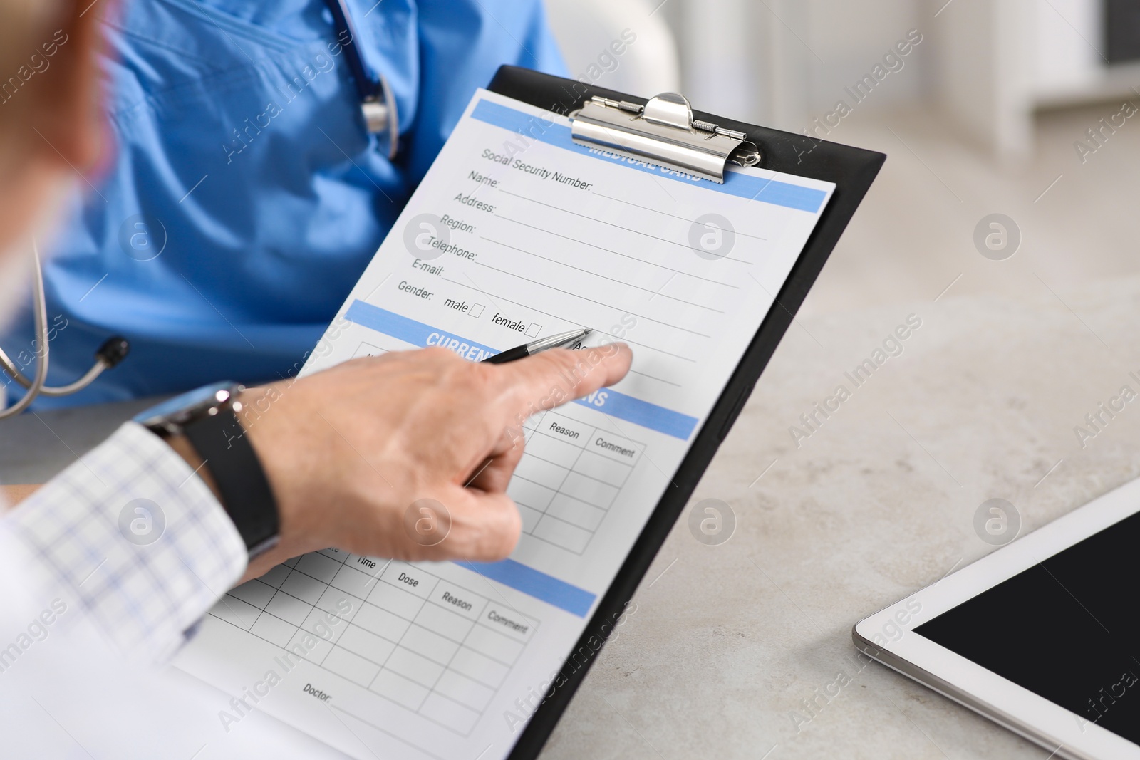 Photo of Doctor showing medical card to patient at table in clinic, closeup