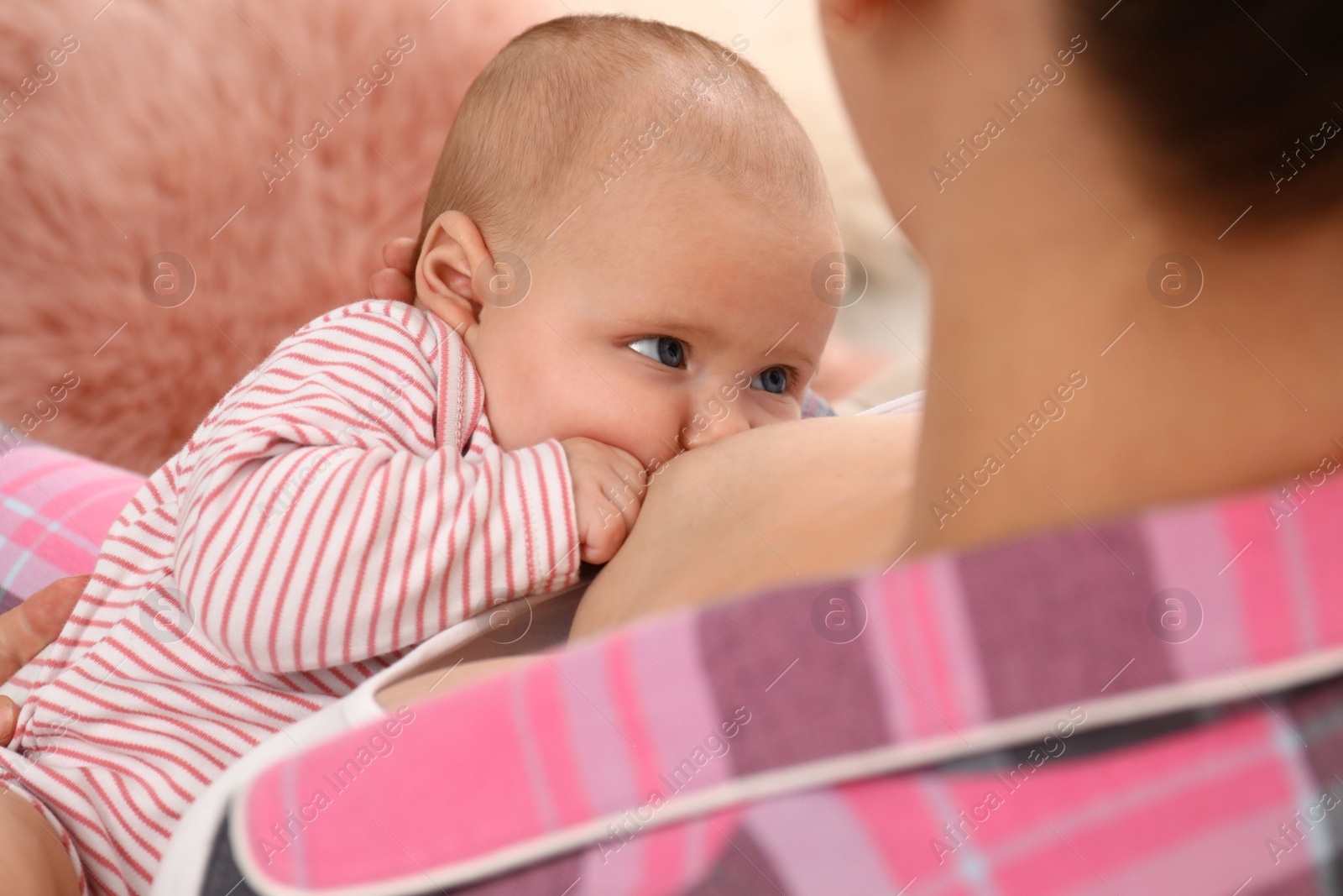 Photo of Young woman breastfeeding her little baby at home, closeup