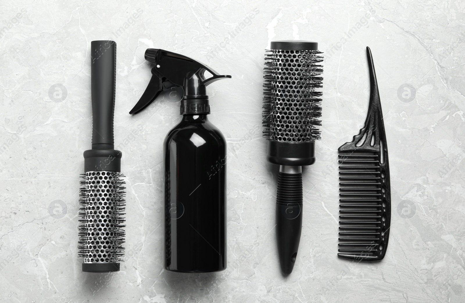 Photo of Hair brushes, comb and spray on light grey marble background, flat lay