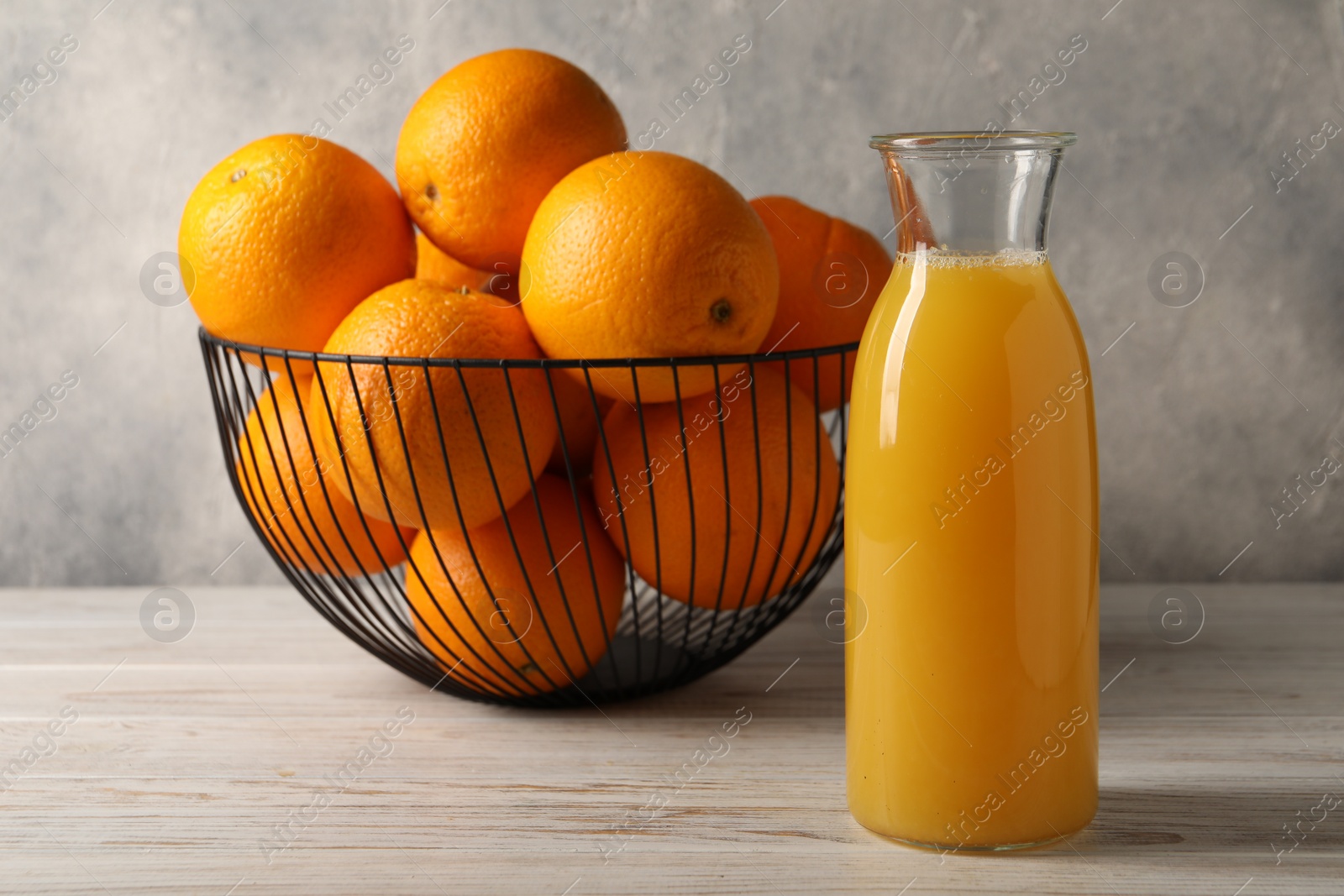 Photo of Tasty fresh oranges and juice in jug on white wooden table