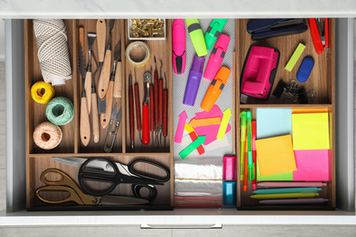 Photo of Stationery and sewing accessories in open desk drawer, top view
