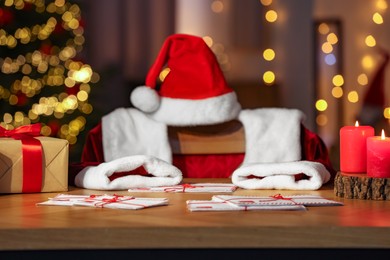 Santa's Claus workplace. Gift boxes, letters on table and costume in room with Christmas tree