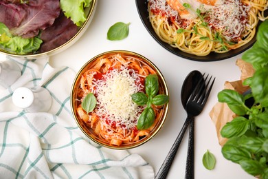 Delicious pasta with tomato sauce, basil and parmesan cheese on white table, flat lay