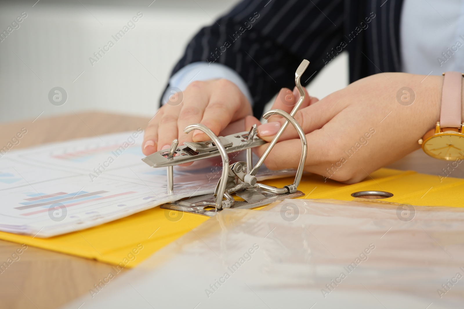 Photo of Businesswoman putting document into file folder at wooden table in office, closeup