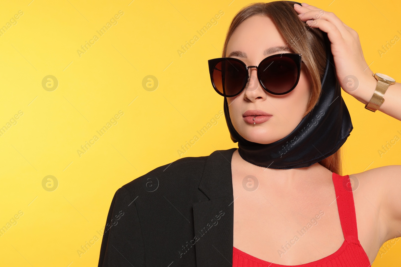 Photo of Young woman with lip piercing and sunglasses on yellow background. Space for text