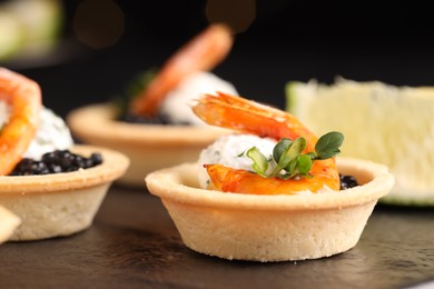 Delicious canapes with shrimps and black caviar on table, closeup