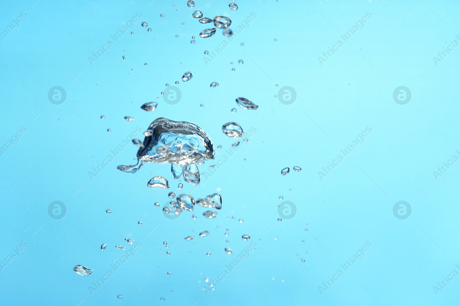 Photo of Air bubbles in water on light blue background