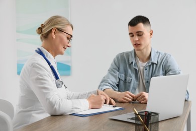 Photo of Professional doctor writing prescription at wooden table in clinic