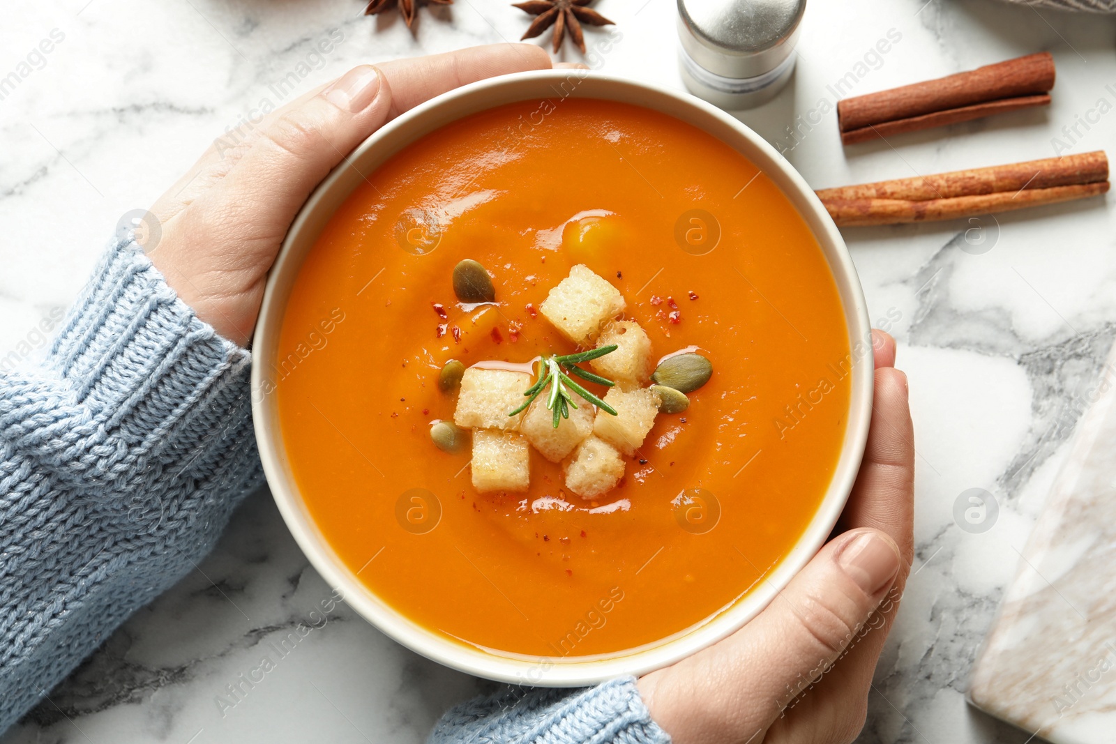 Photo of Woman with bowl of tasty sweet potato soup at table, top view