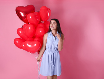 Photo of Beautiful young woman with heart shaped balloons on pink background. Valentine's day celebration