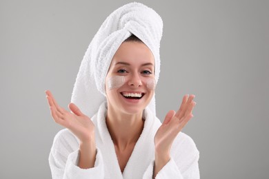 Photo of Woman with cosmetic product on her face against grey background. Spa treatments
