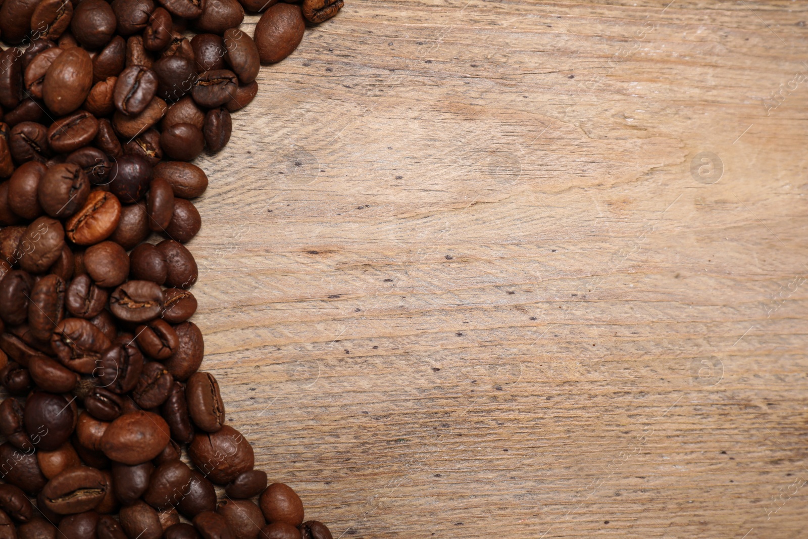 Photo of Roasted coffee beans on wooden table, flat lay. Space for text