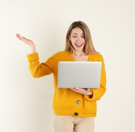 Portrait of young woman in casual outfit with laptop on light background. Space for text