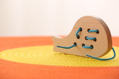 Motor skills development. Wooden lacing toy on color mat, closeup. Space for text