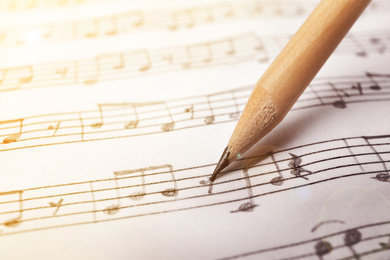 Sheet with music notes and pencil as background, closeup