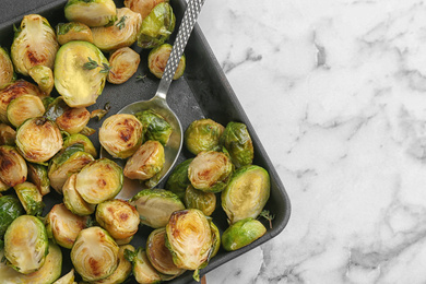 Photo of Delicious roasted brussels sprouts on white marble table, top view. Space for text